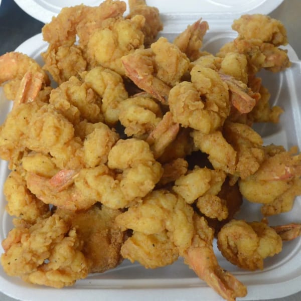 A white takeout container filled with a generous serving of golden-brown fried shrimp from Rahim's Seafood.