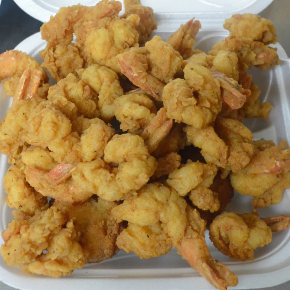 A white takeout container filled with a generous serving of golden-brown fried shrimp from Rahim's Seafood.