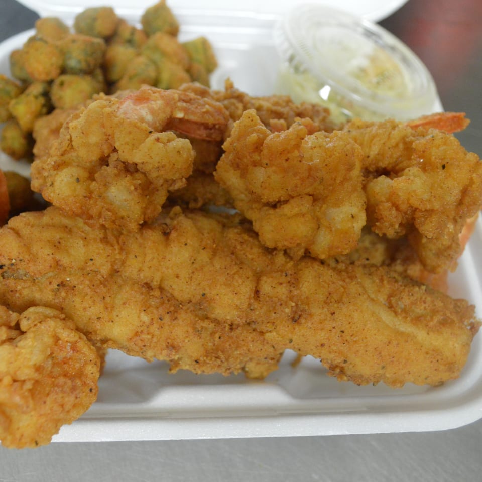 Rahim's Seafood fried fish and shrimp combo with fried okra and tartar sauce in a takeout container.