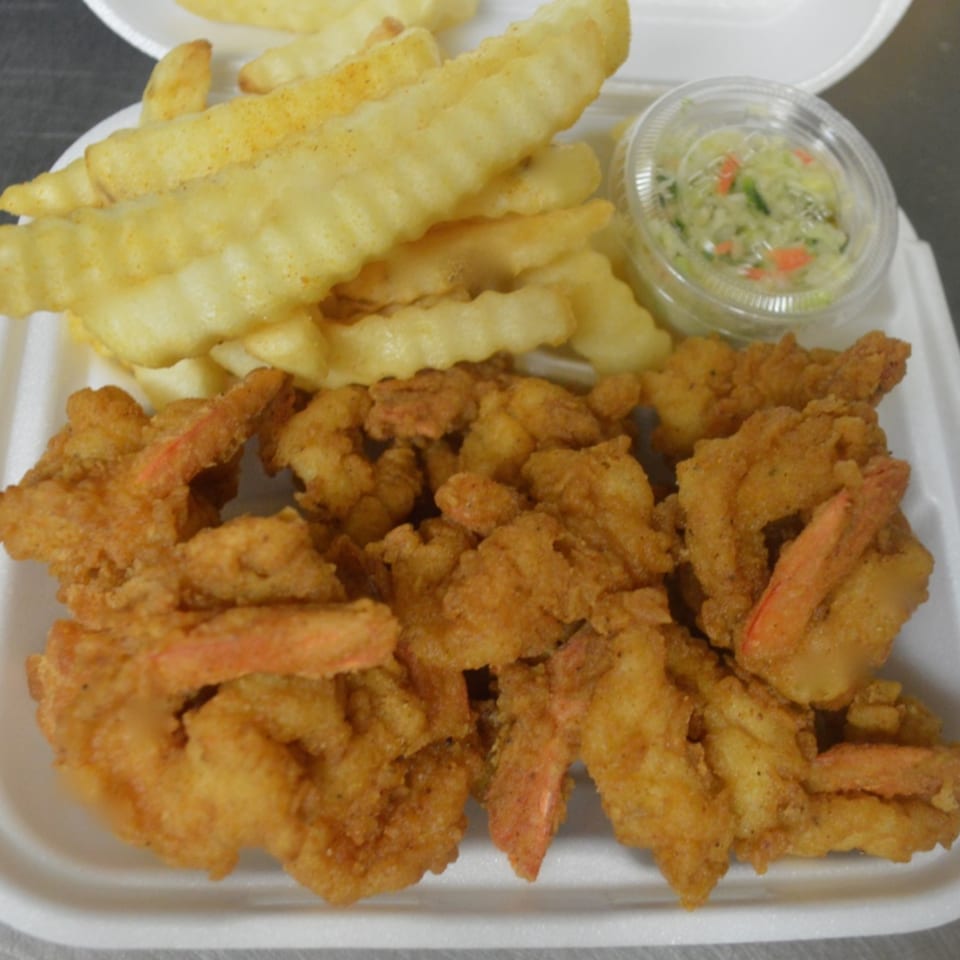 Fried shrimp and crinkle-cut fries with a side of coleslaw in a white takeout container.